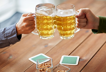 Image showing close up of hands clinking beer mugs at bar or pub