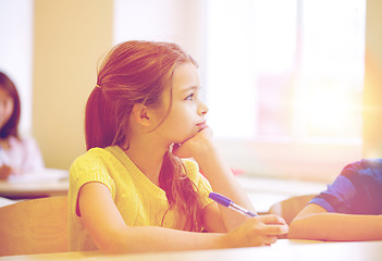 Image showing school girl with pen being bored in classroom