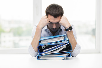 Image showing sad businessman with stack of folders at office