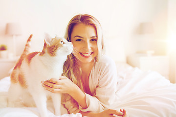 Image showing happy young woman with cat in bed at home