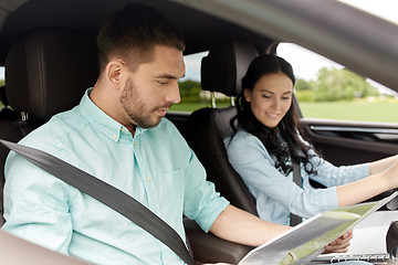 Image showing happy man and woman with road map driving in car