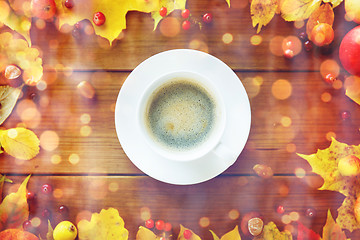 Image showing close up of coffee cup on table with autumn leaves