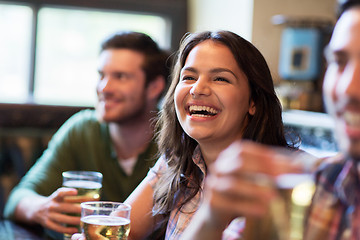 Image showing happy woman with friends drinking beer at pub