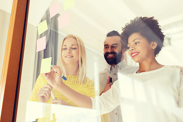 Image showing happy creative team writing on stickers at office