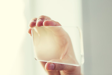 Image showing close up of male hand with transparent smartphone