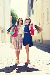 Image showing happy women with shopping bags walking in city 