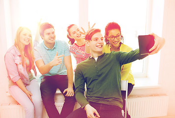 Image showing smiling students making picture with tablet pc