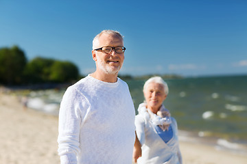 Image showing happy senior couple holding hands on summer beach