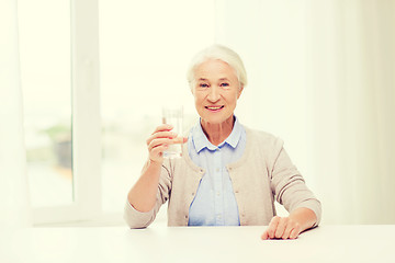Image showing happy senior woman with glass of water at home