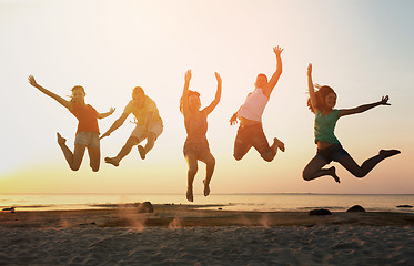 Image showing smiling friends dancing and jumping on beach