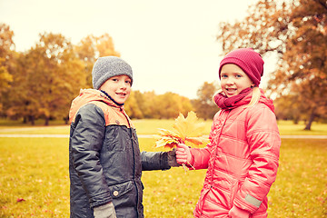 Image showing little boy giving autumn maple leaves to girl