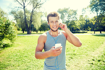 Image showing happy man with earphones and smartphone at park