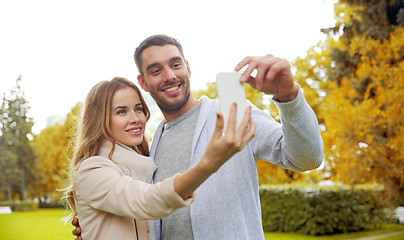 Image showing happy couple with smartphone taking selfie in park