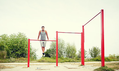 Image showing young man exercising on horizontal bar outdoors