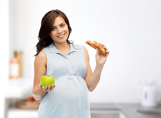 Image showing happy pregnant woman with apple and croissant