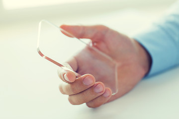 Image showing close up of male hand with transparent smartphone