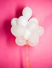 Image showing close up of white helium balloons over pink