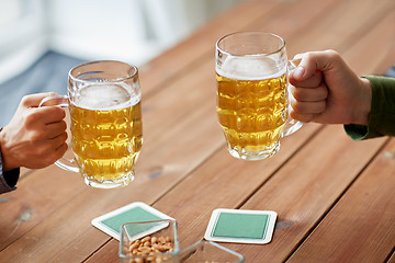 Image showing close up of hands with beer mugs at bar or pub