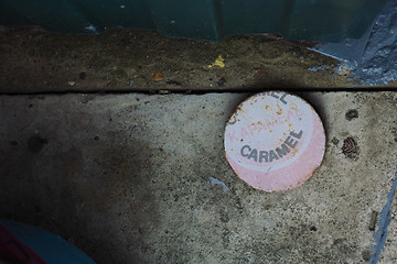 Image showing Flat round object with caramel word on cement ground