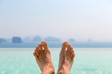 Image showing closeup of male feet over sea and sky on beach