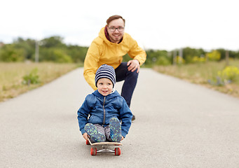 Image showing happy father and little son riding on skateboard