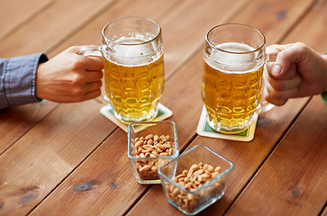 Image showing close up of hands with beer mugs at bar or pub