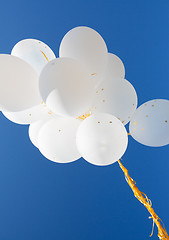 Image showing close up of white helium balloons in blue sky