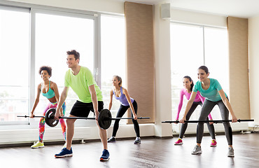 Image showing happy people exercising with barbell bars in gym