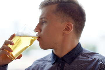 Image showing close up of young man drinking beer from glass