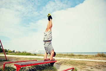 Image showing young man exercising on bench outdoors