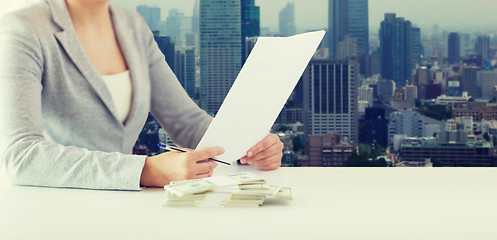 Image showing close up of female hands with money and tax report