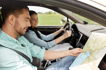 Image showing happy man and woman with road map driving in car