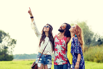 Image showing happy hippie friends pointing finger outdoors