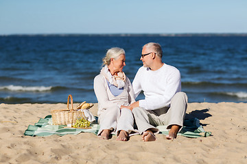 Image showing happy senior couple having picnic on summer beach