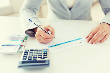 Image showing close up of hands counting money with calculator