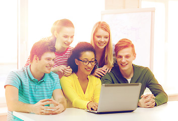 Image showing smiling students looking at laptop at school