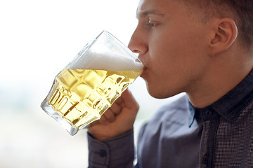 Image showing close up of young man drinking beer from glass mug