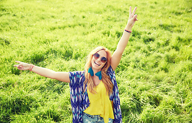 Image showing smiling young hippie woman dancing on green field