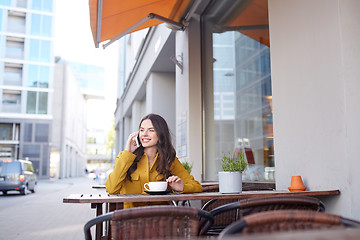 Image showing happy woman calling on smartphone at city cafe