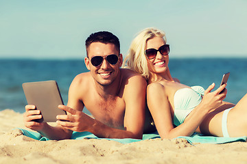 Image showing happy couple with tablet pc sunbathing on beach