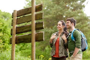 Image showing smiling couple at signpost with backpacks hiking