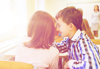 Image showing smiling schoolgirl whispering to classmate ear