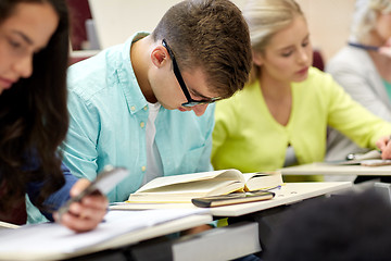 Image showing male student in glasses reading book at lecture