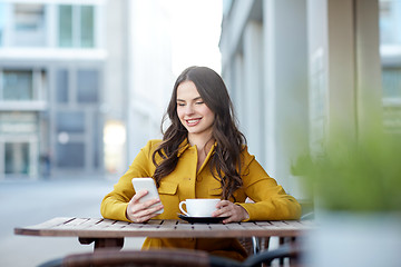 Image showing happy woman texting on smartphone at city cafe