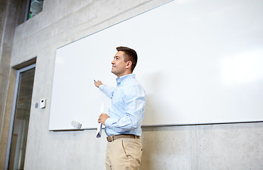 Image showing teacher pointing marker to white board at lecture