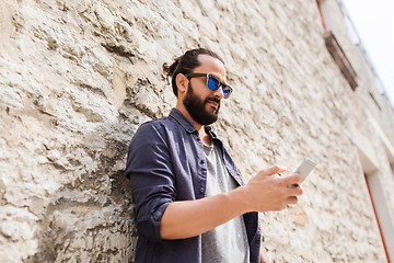 Image showing man texting message on smartphone at stone wall