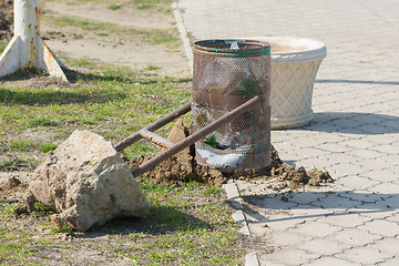 Image showing Torn out of the earth a broken wheelie bin with concrete base