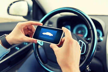 Image showing close up of male hands with car icon on smartphone