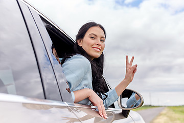 Image showing happy woman driving in car showing peace sign