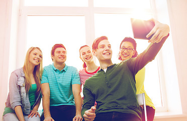 Image showing smiling students making picture with tablet pc